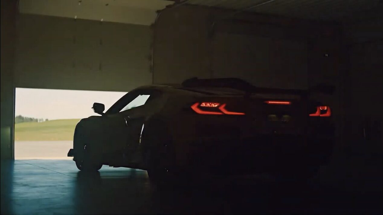 A Black Chevy Corvette with Illuminated Taillights Parked Inside a Dimly Lit Garage with Light Shining Through the Entrance.