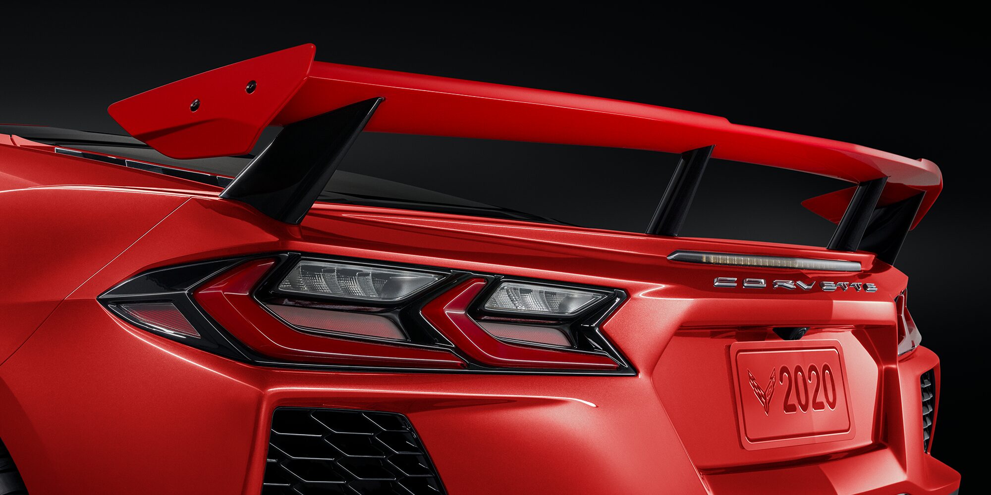 A Rear View of a Red Chevrolet Corvette Featuring an Aggressive Spoiler, Distinctive Tail Lights, and Corvette Badge.
