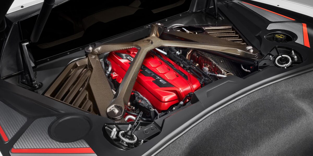 A Close-Up of a Chevrolet Corvette Engine Bay Showcasing a Red Engine Cover with Visible Metallic Components and Carbon Fiber Accents.