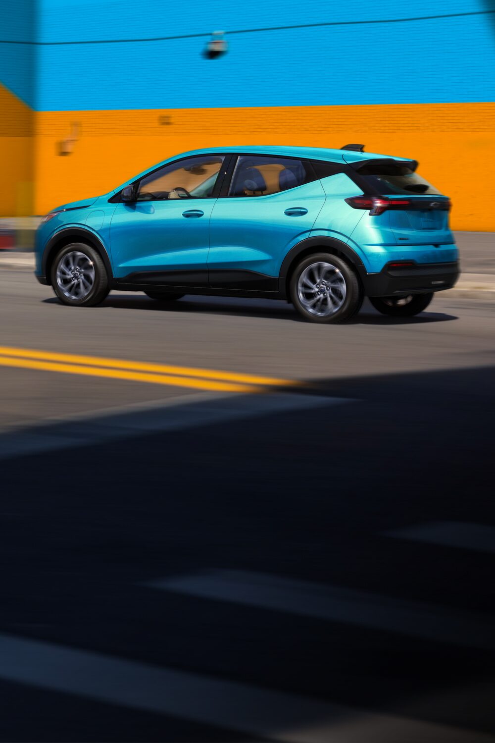2027 Chevrolet Bolt in Marina Blue Metallic Parked in Front of a Blue and Orange Wall