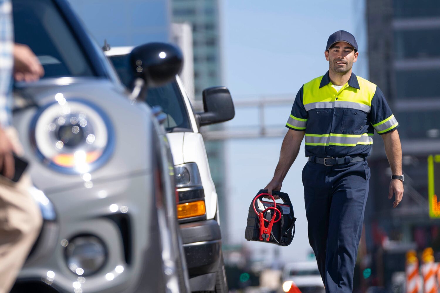 A Repairman Walking Past Parked Cars in a City