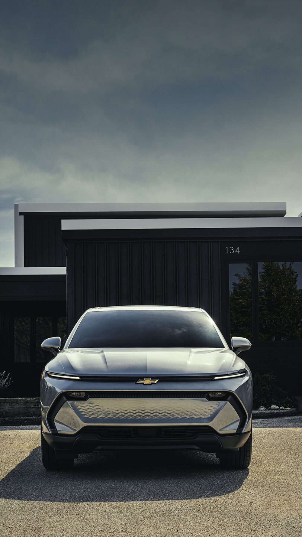 A Silver Chevrolet Equinox EV Parked in Front of a Modern Dark Building.
