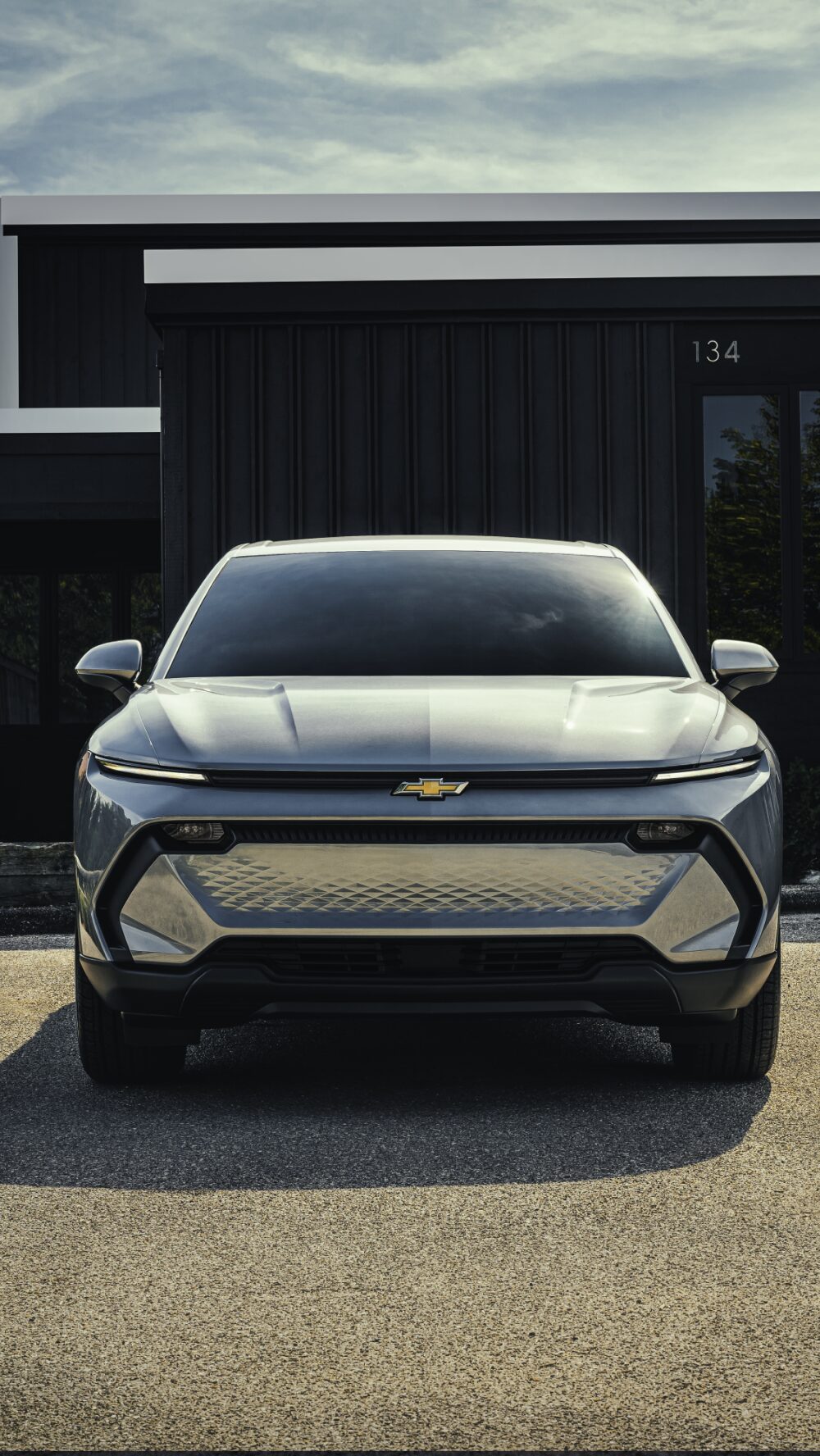 A Silver Chevrolet Equinox EV Parked in Front of a Modern Dark Building.