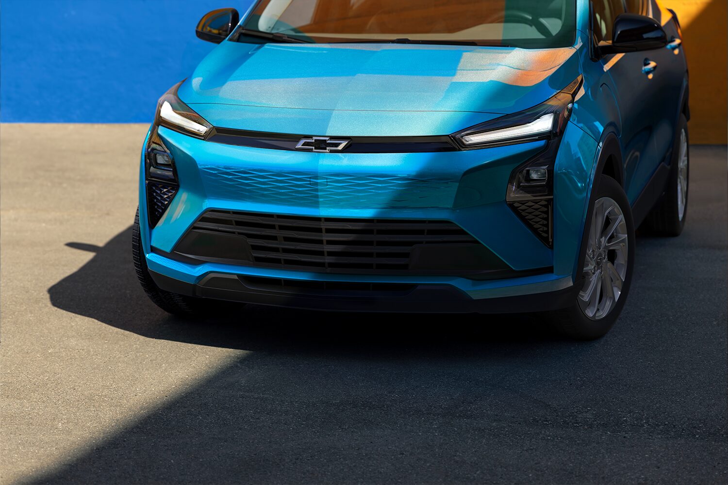 A Front View Close-Up of a Marina Blue Metallic 2027 Chevrolet Bolt, Highlighting the New Front Fascia, Black Grille, and Prominent Chevrolet Bowtie Logo in the Center.