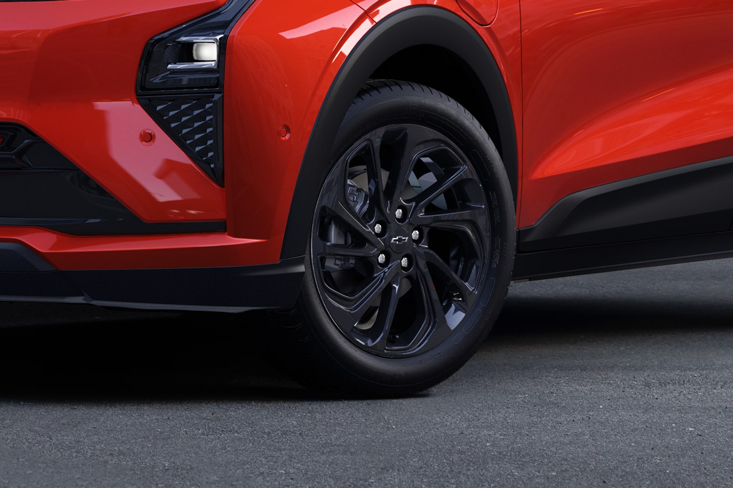 A Close-Up of the Front Wheel of a Habanero 2027 Chevrolet Bolt RS, Showing the Black Multi-Spoke Wheel with a Black Chevrolet Bowtie in the Center.