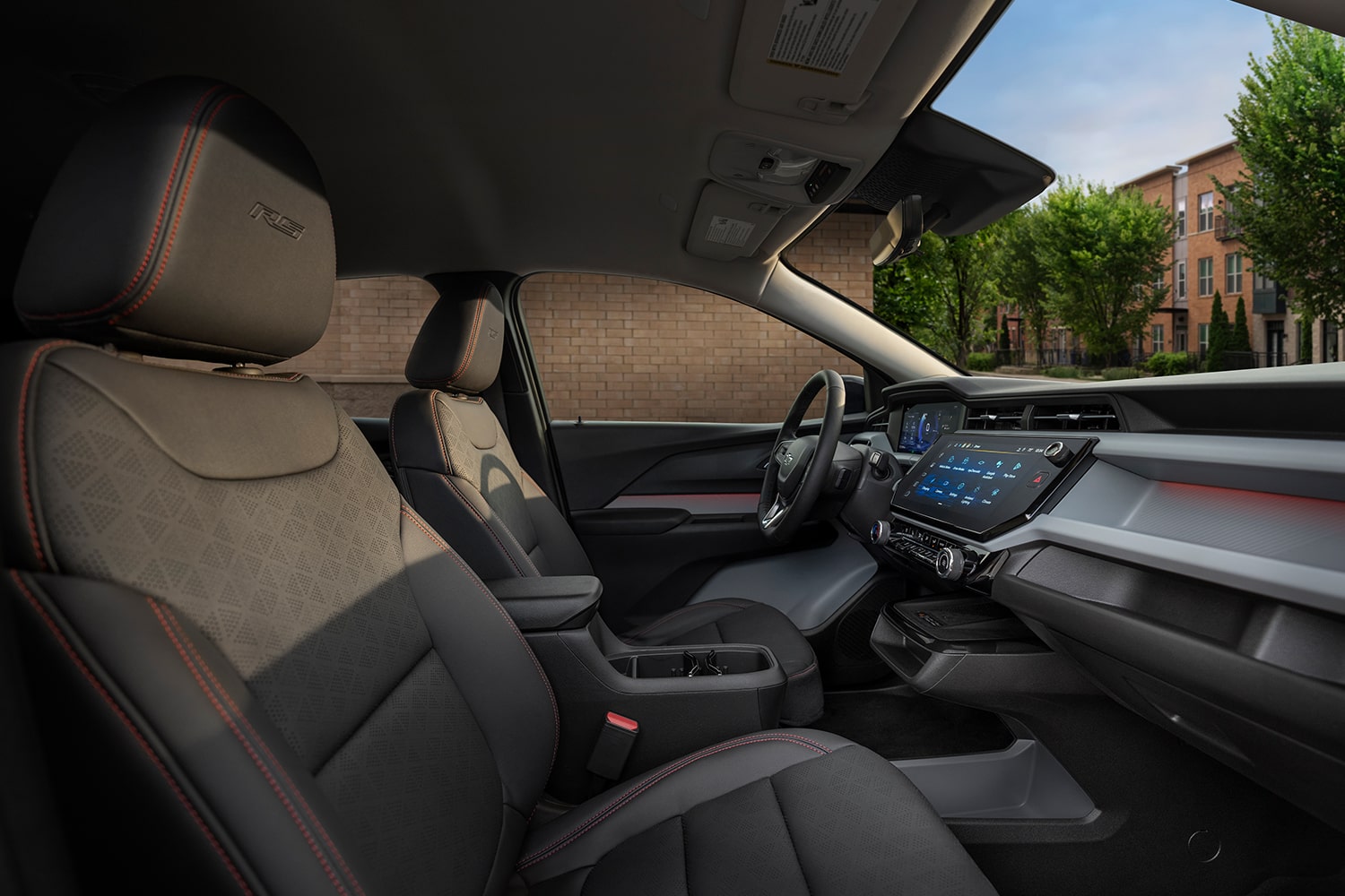 The Interior of a 2027 Chevrolet Bolt RS, Showing the Black Evotex Front Seat with Red Stitching and the RS Badge on the Headrest.