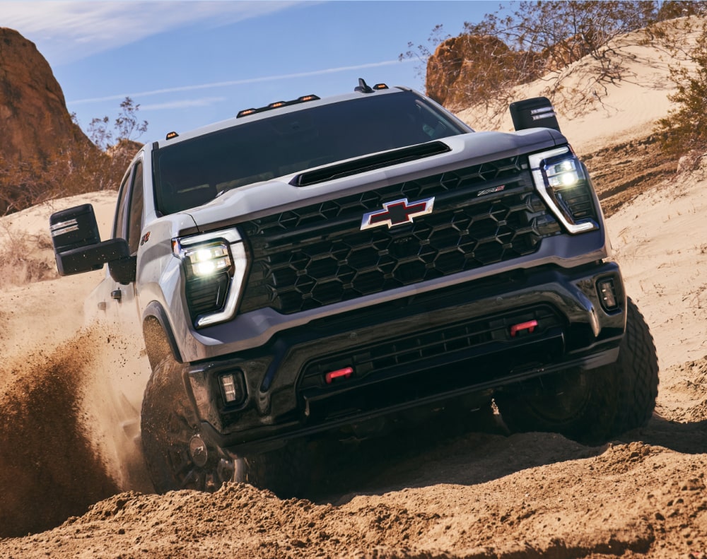 2025 Chevy Silverado HD Driving Through Muddy Terrain in a Western Landscape