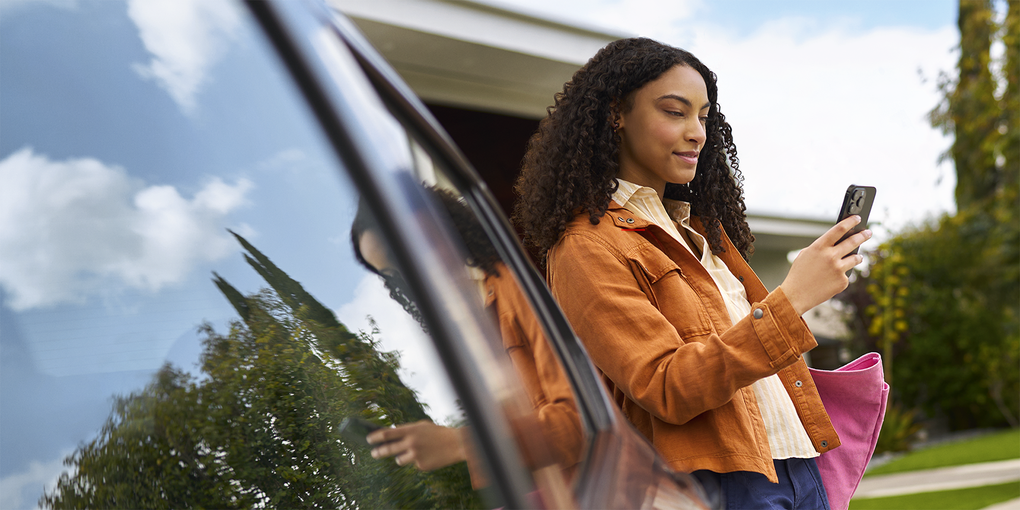 Woman Leaning Against Her Car On Her Phone Using OnStar Features