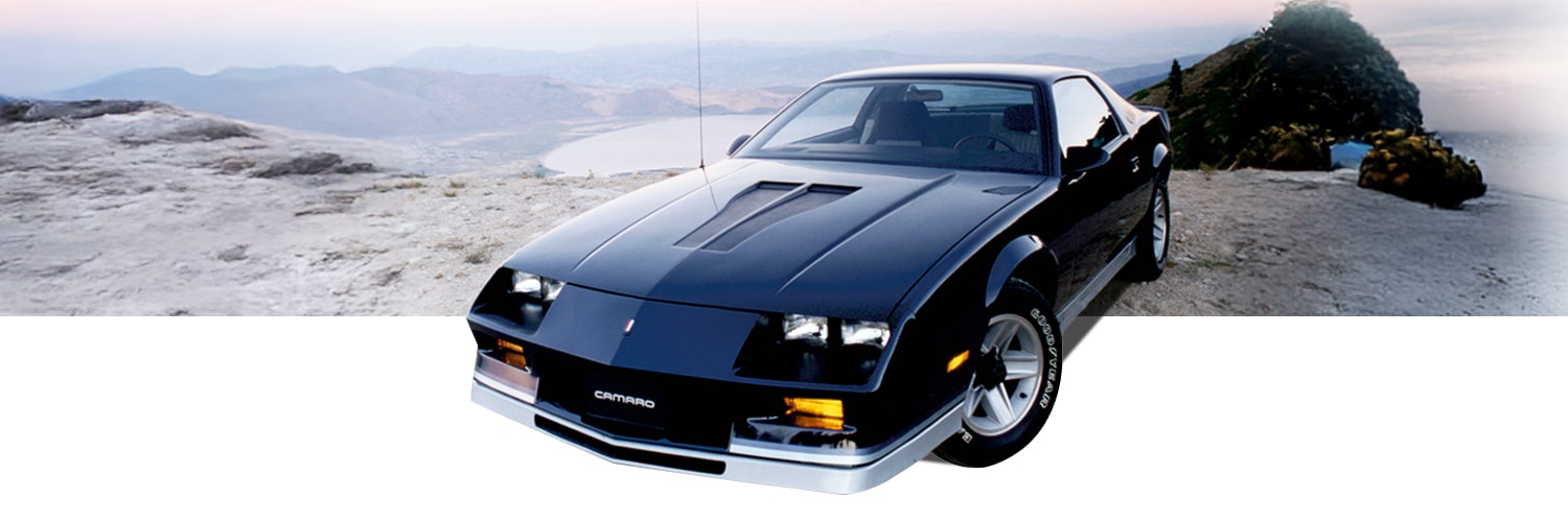 Black Chevrolet Camaro Vehicle Parked on a Mountain Overlook with a Lake and Distant Hills in the Background