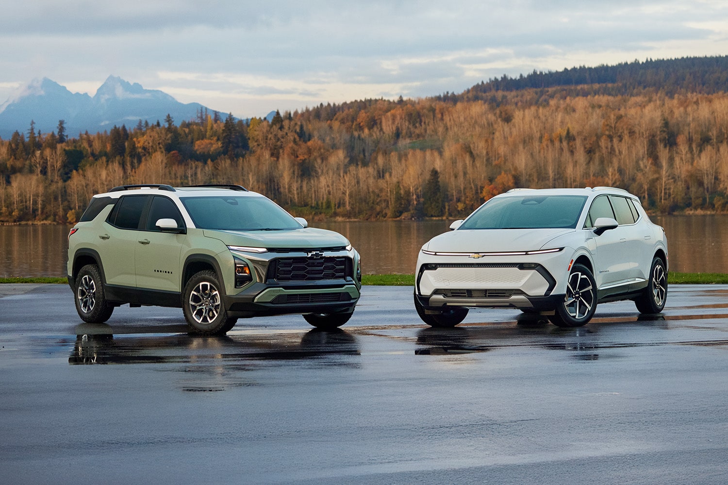Two Green and White Chevrolet Vehicles on a Plain with Trees and Mountains Peaking from Behind