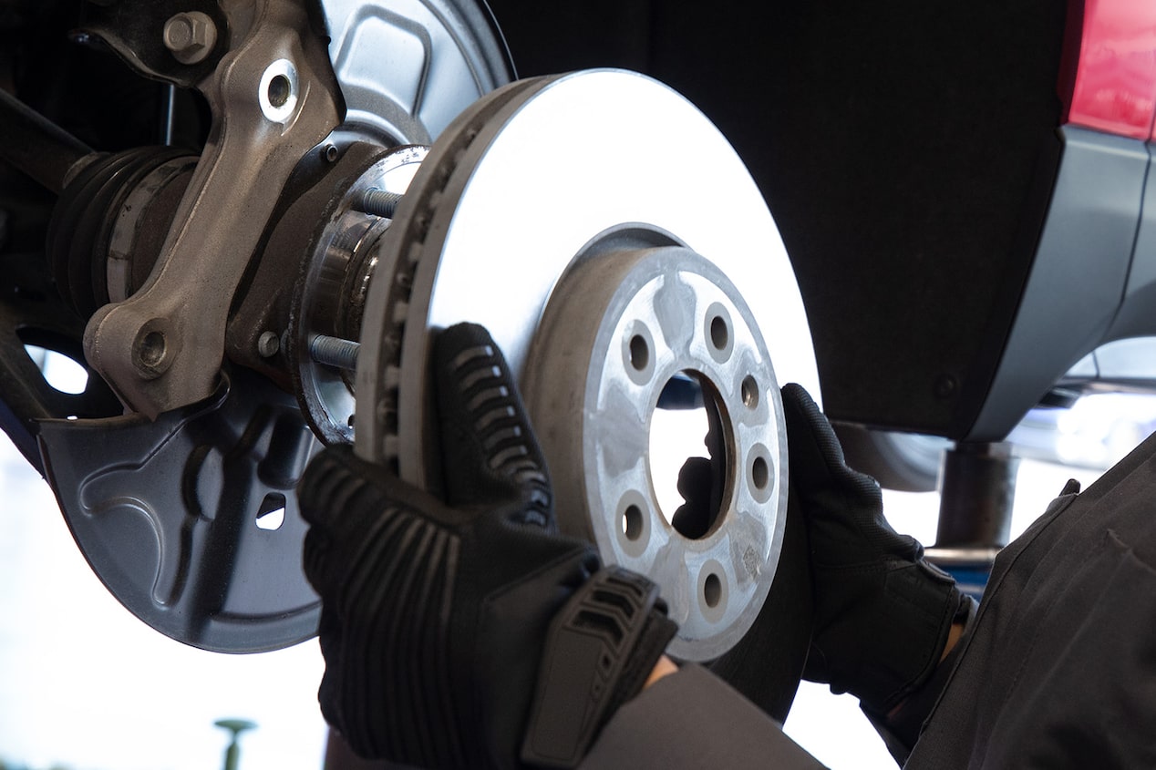 A Mechanic Wearing Black Gloves Working on a Wheel of a Vehicle