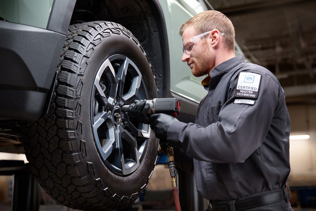 A Certified Technician Installing a New Tire on a Raised Vehicle