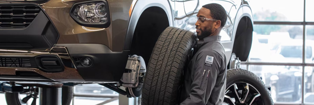 A Mechanic Is Holding a Tire from a Suspended Vehicle
