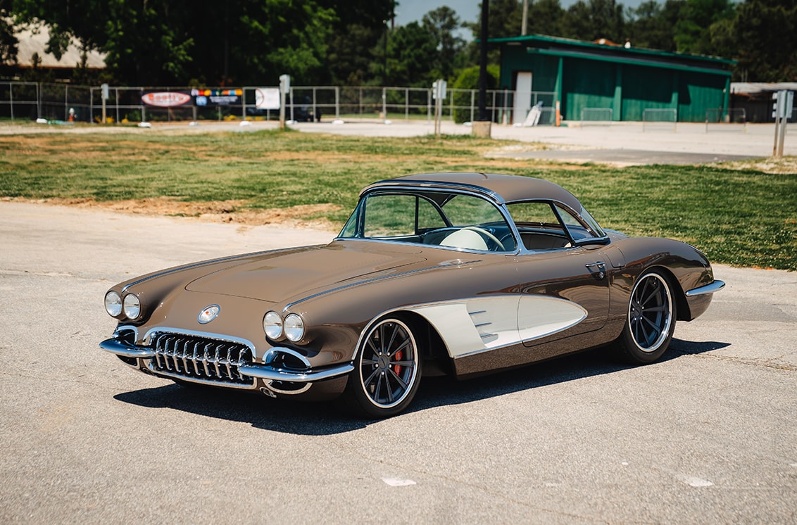 A Side Angled View of a Brown Retro 1958 Chevrolet Corvette Parked on a Gravel Patch.