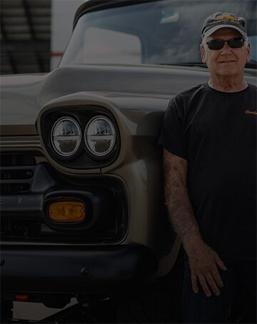 A Man Leaning on an Older Vehicle with the Text Bigger Dreams Bigger Rewards Text to the Left