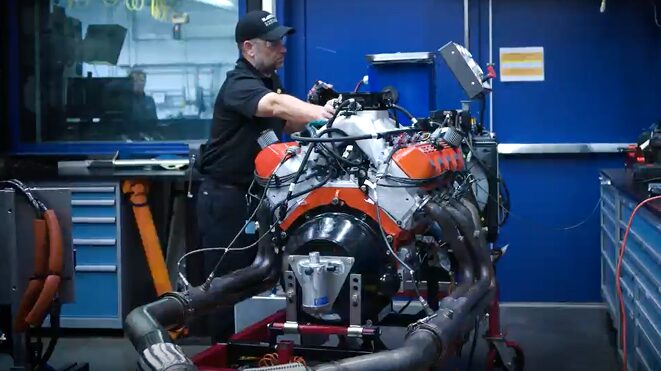 A Person Is Seen Carrying a Heavy Part to the Engine of a Vehicle