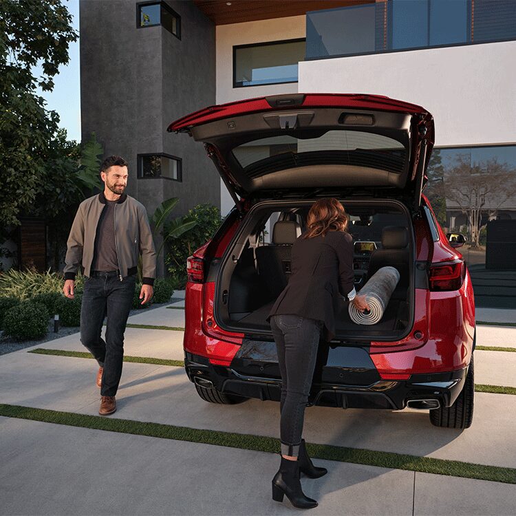 A Woman Putting a Mat Inside the Trunk of a 2026 Red Chevy Blazer