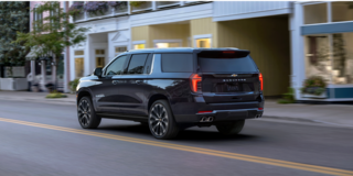 Rear Three-quarters View of the 2026 Chevy Suburban SUV Driving Through the City