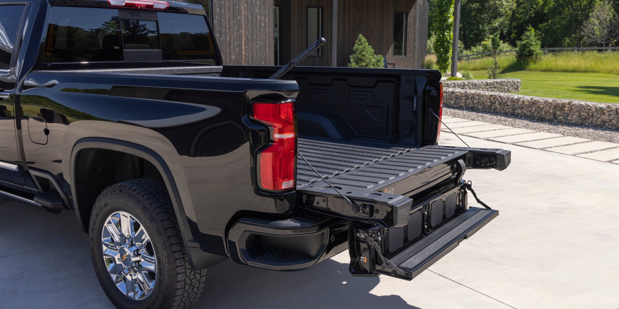 A Black Chevy Silverado LD Parked in a Driveway with Its Multi-Flex Tailgate Open Showing the Truck Bed.