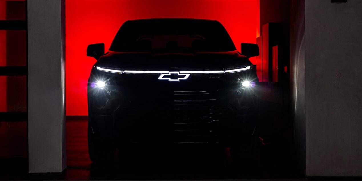 Chevy Silverado EV Parked in a Dark Garage with Headlights and Logo Illuminated