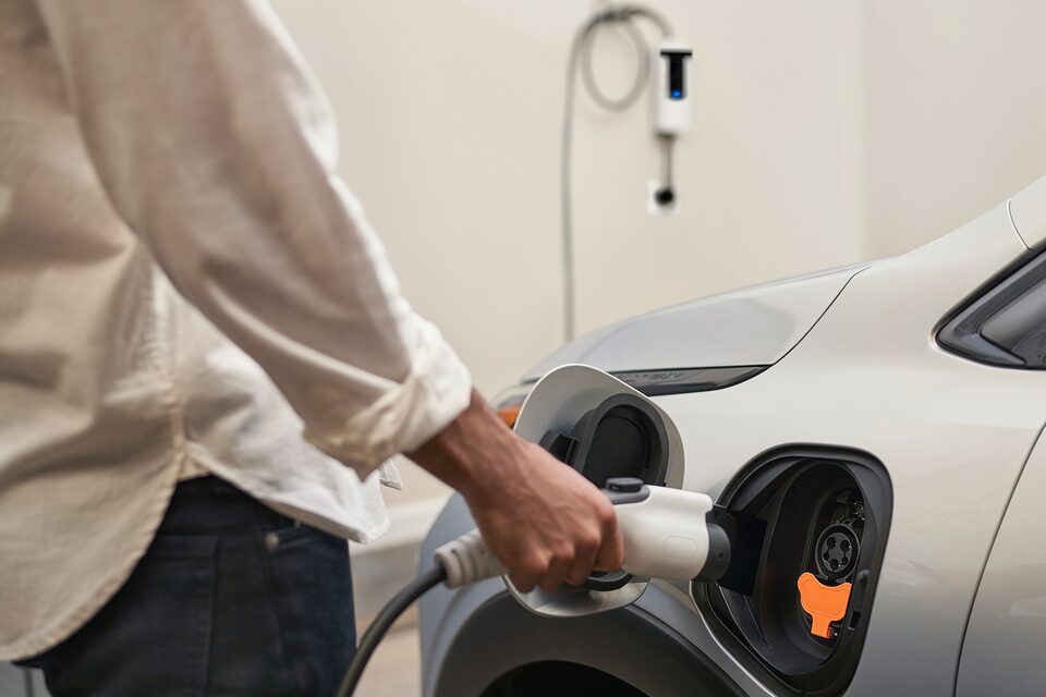 A Person Plugging in their Charger at Home in a Garage