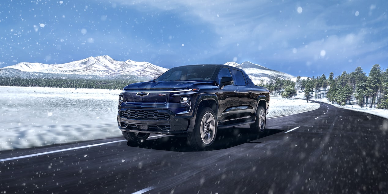 Chevy Silverado EV Driving on a Road with a Snowy Landscape in the Background