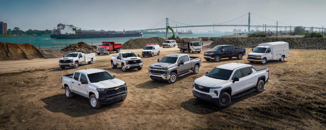 Chevrolet Fleet Lineup Parked in a Field with A Large Bridge in the Background