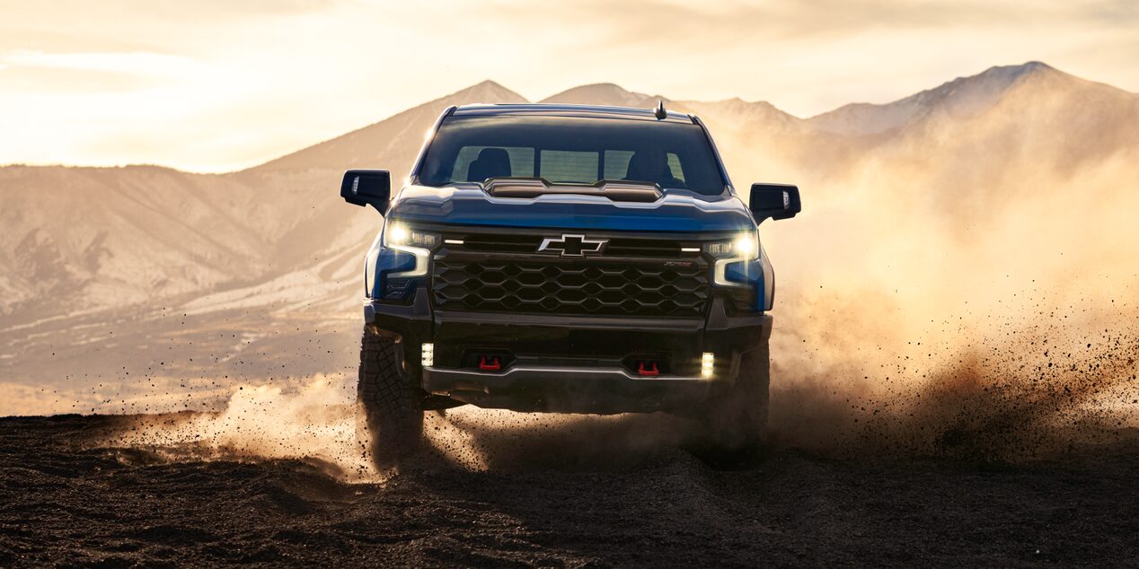 Blue ZR2 Driving in Desert at Sunset