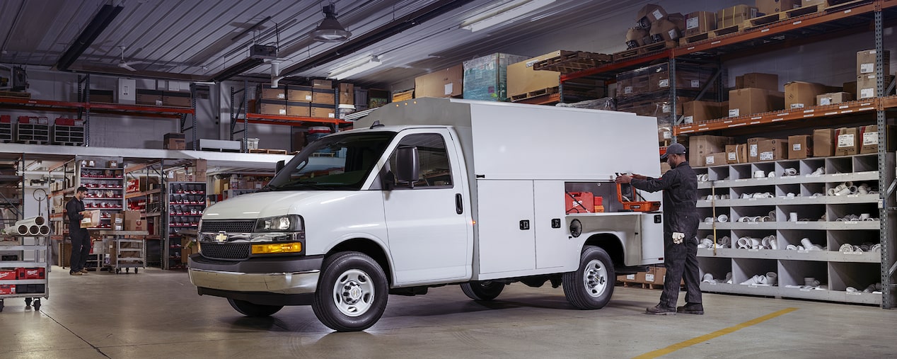 Man Storing Work Equipment in Exterior Storage Compartment on His 2025 Chevy Commercial Express Cutaway 