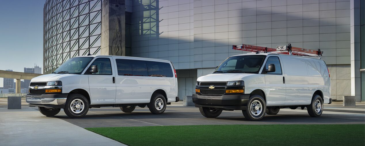 2025 Chevy Commercial Express Vans Parked Outside Glass Office Building