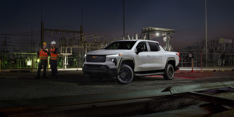 Three quarters view of a 2025 Chevy Silverado EV stationed by the road at night