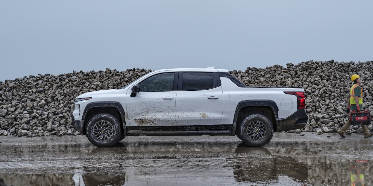 Side view of a white 2025 Chevy Silverado EV on a wet plain