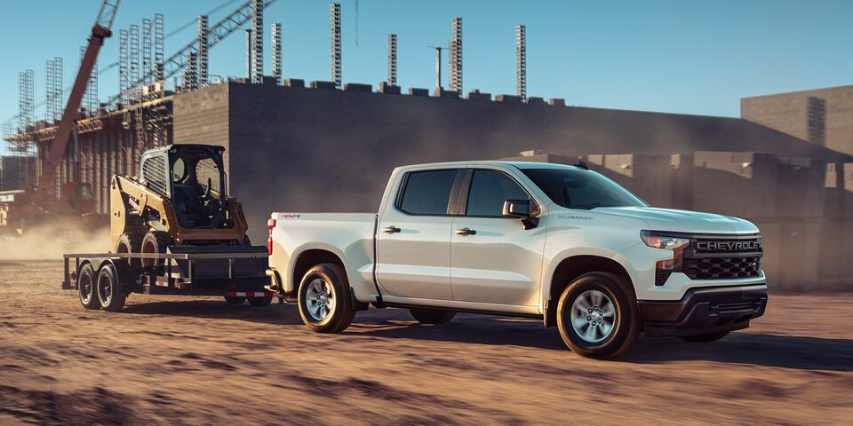 2025 Chevrolet Silverado Towing a Skid Loader on a Trailer