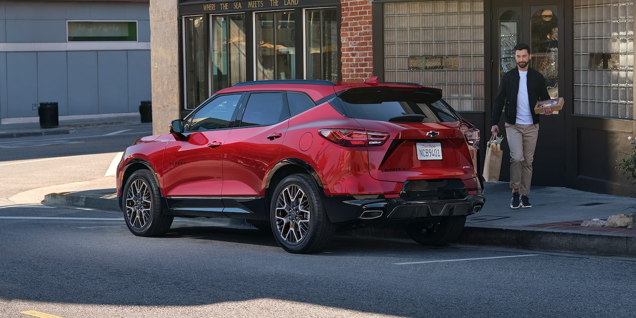 Man Walking Toward His 2025 Red Chevy Blazer Parked at a Sho