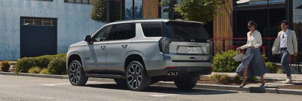 A Couple Walks Toward Their 2025 Chevy Tahoe Parked Out Front of a Shop