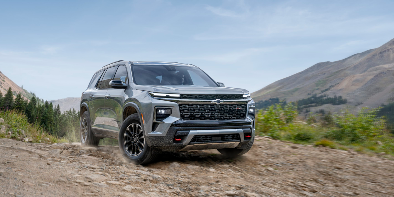 Low Three Quarters View of a 2025 Chevy Traverse on an Dirt Road Surrounded by Mountains