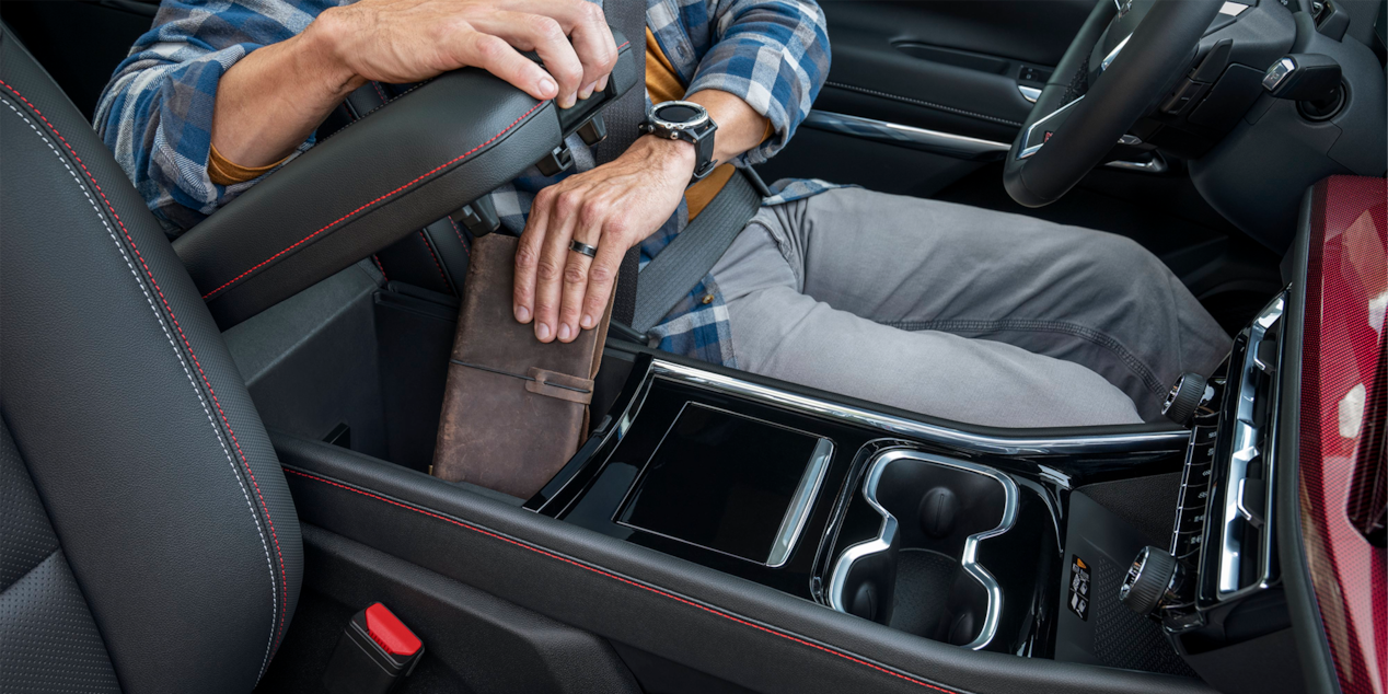 A Man Putting His Wallet in the Arm Resting Compartment of the 2025 Chevy Traverse