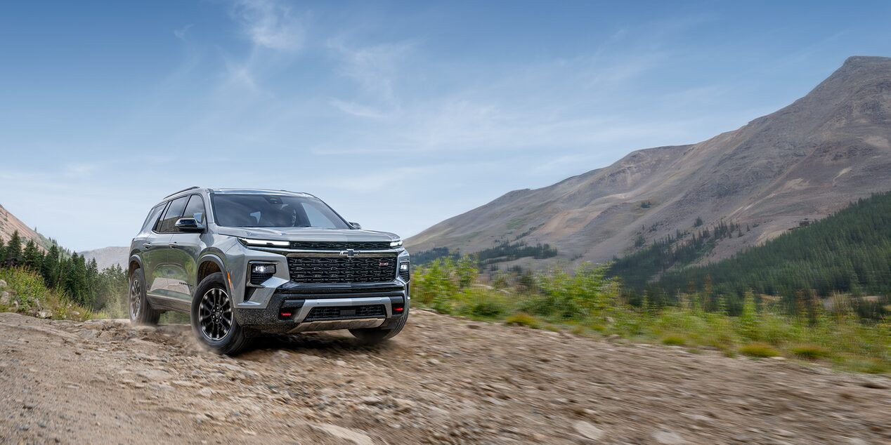 Low Three Quarters View of a 2025 Chevy Traverse on a Dirt Road Surrounded by Mountains