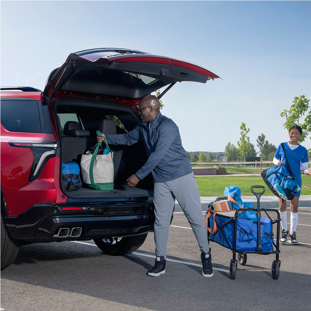 A Man Taking Out Bags from the Trunk of a Red 2025 Chevy Traverse