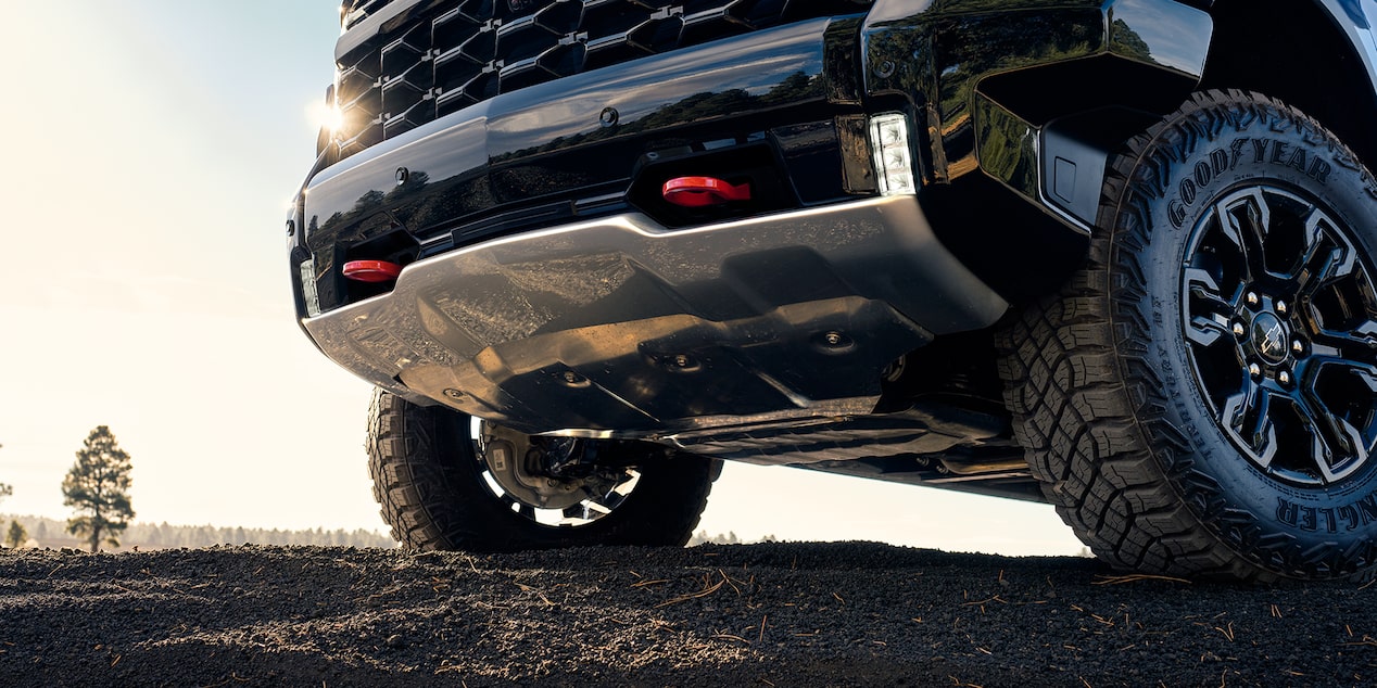 Front Grille of a Blue 2025 Chevy Silverado on a Muddy Road