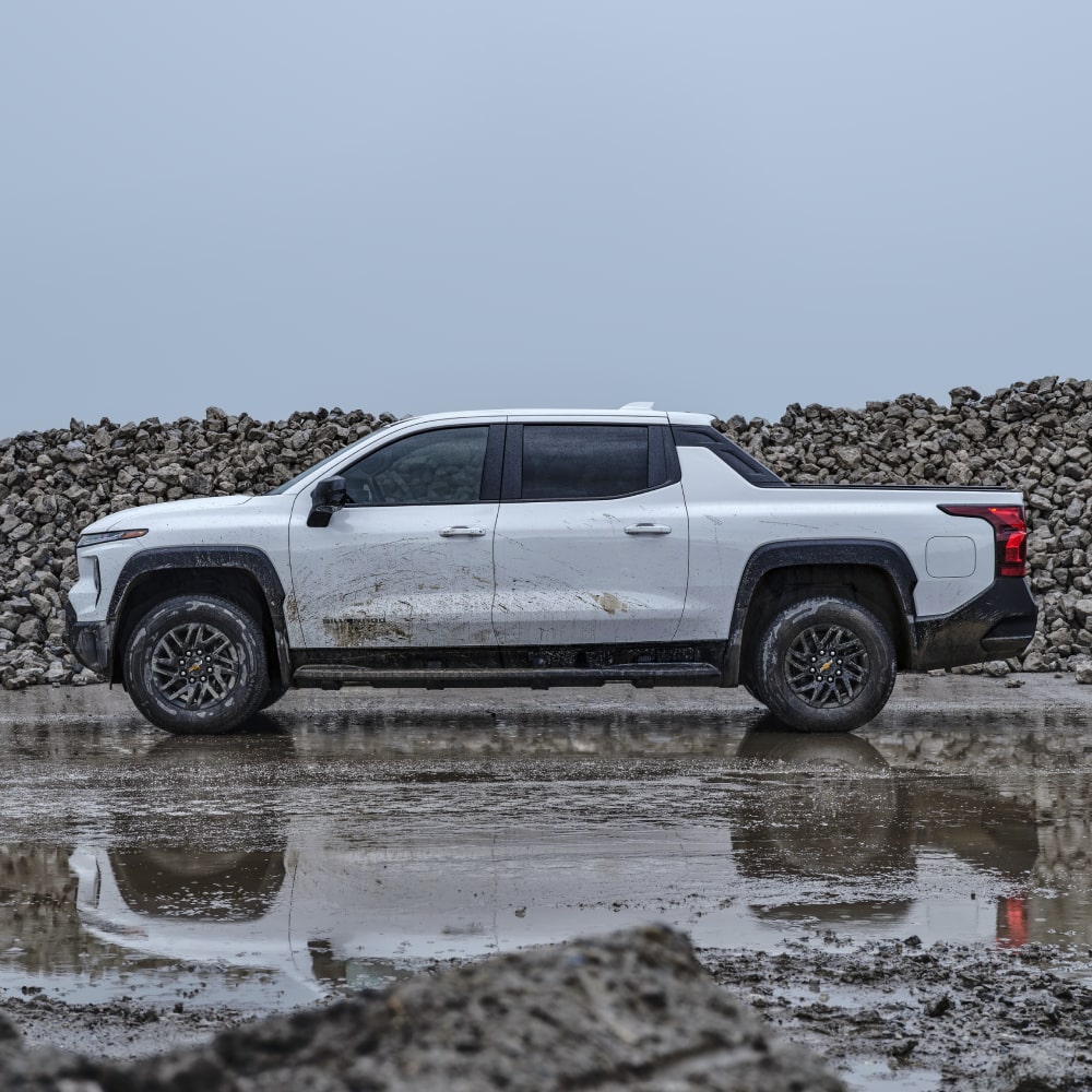 2026 Chevy Commercial Silverado EV Parked Near a Pile of Rocks on a Construction Site on a Rainy Day