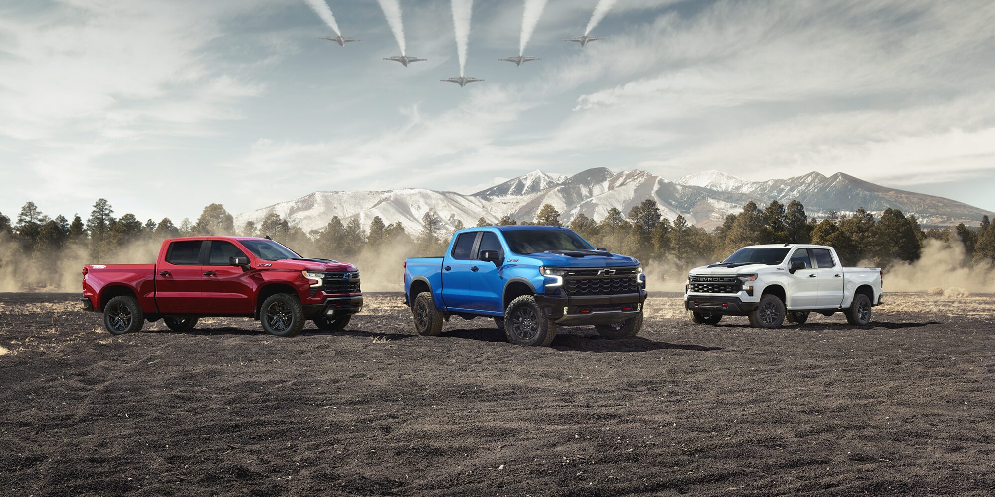 Three Chevrolet Silverado trucks parked near each other outdoors.