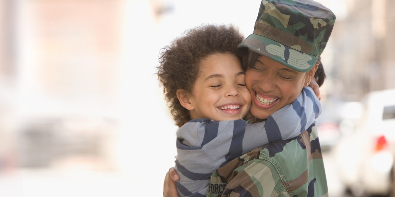 Close-up of a Military Member Reuniting with a Child Hugging and Smiling
