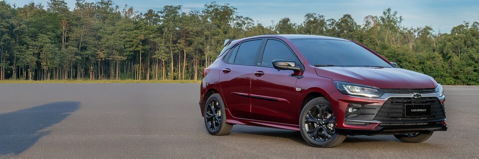 Chevrolet Onix hatch em vista totalmente frontal com vegetação ao fundo.