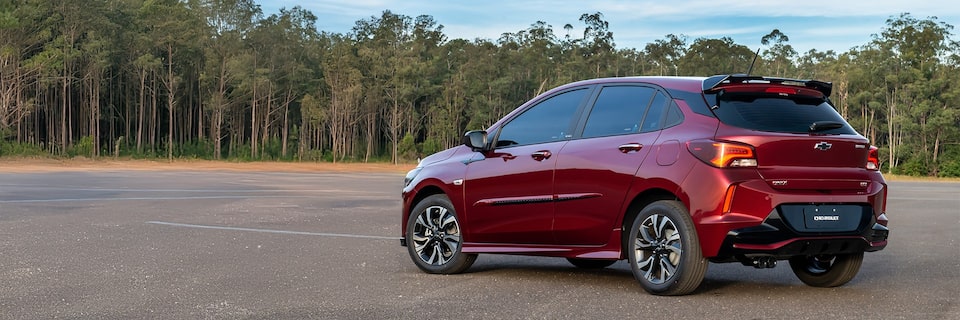 Chevrolet Onix hatch em vista de traseira e lateral esquerda com destaque para o design esportivo das lanternas.