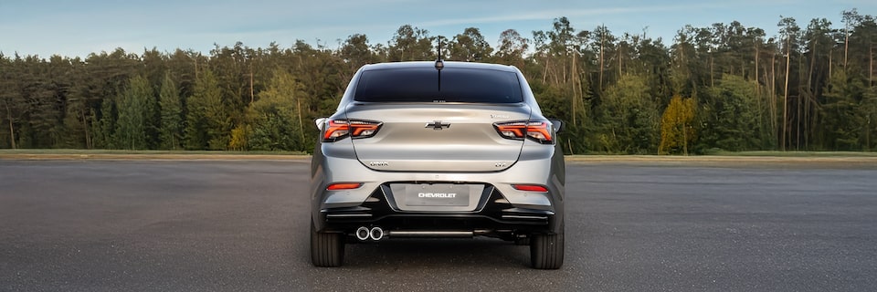 Chevrolet Onix Plus em vista totalmente traseira com destaque para as lanternas e o emblema da marca.