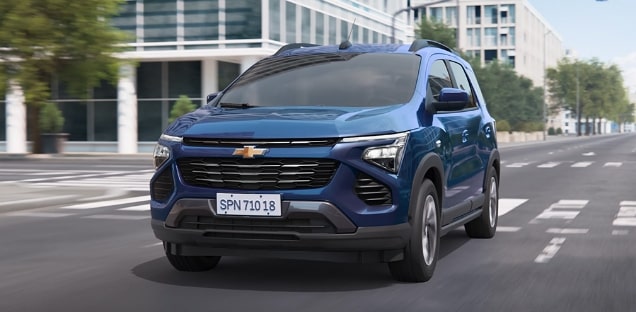 Imagem do novo Chevrolet Spin, na cor Azul Boreal, percorrendo uma avenida.