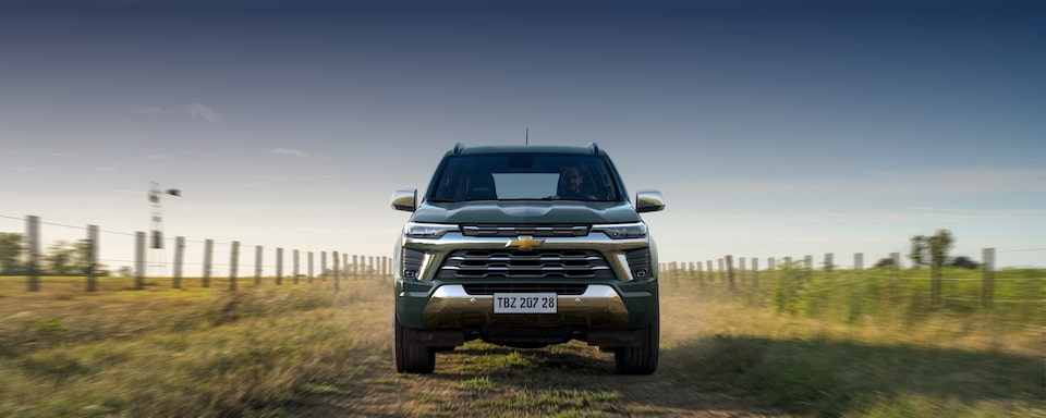 Imagem do novo SUV Chevrolet Trailblazer High Country, cinza topázio, andando em uma estrada de terra, em ambiente rural.