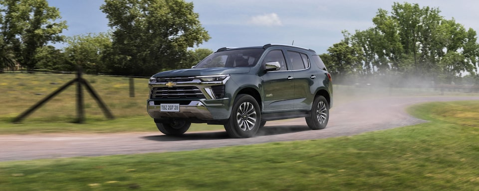 Imagem do novo SUV Chevrolet Trailblazer High Country, cinza topázio, andando em uma estrada de terra, em ambiente rural, levantando poeira da pista.