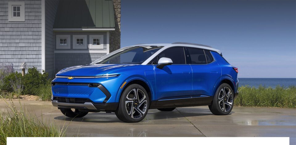 Equinox EV parado em frente a uma casa com o mar ao fundo